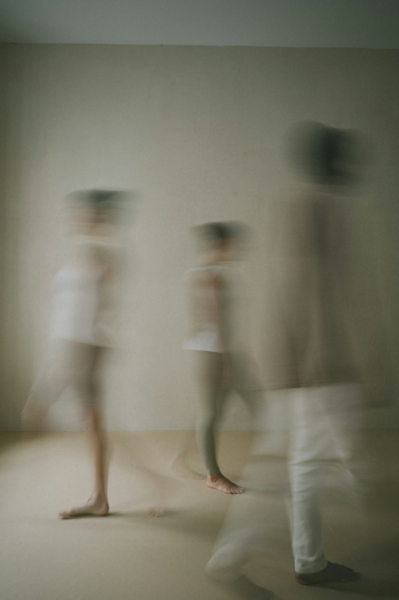 Three blurred out individuals walking to separate corners of a room